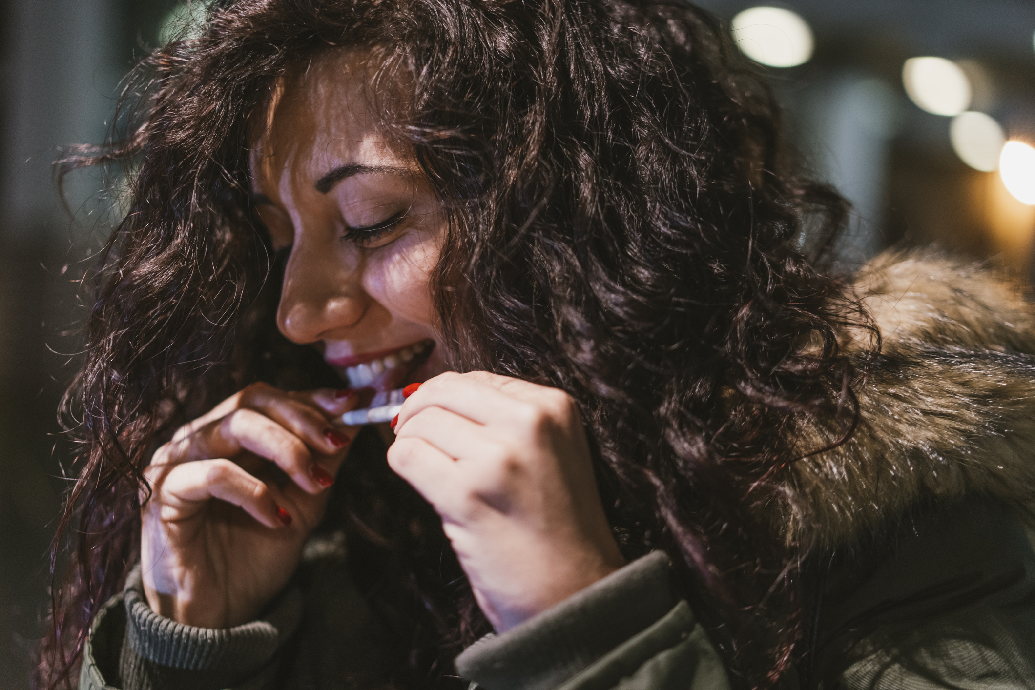 Young adult woman rolling a joint outdoors in New Brunswick at night